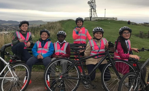 a group of children with bikes sitting on a bench on top of a hill